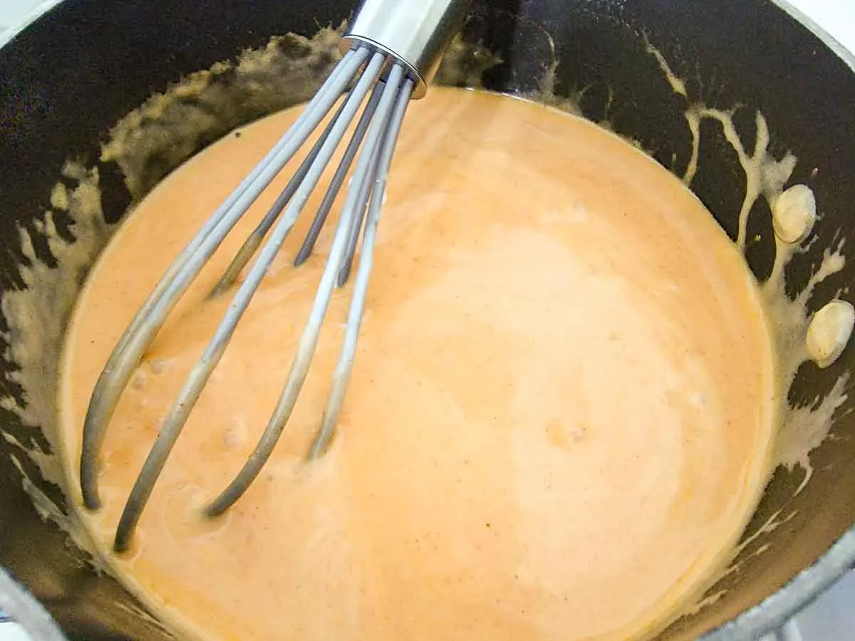 heavy cream and enchilada sauce cooking in a skillet.