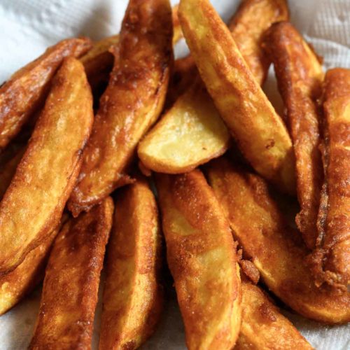Battered Potato Wedges on paper towel.