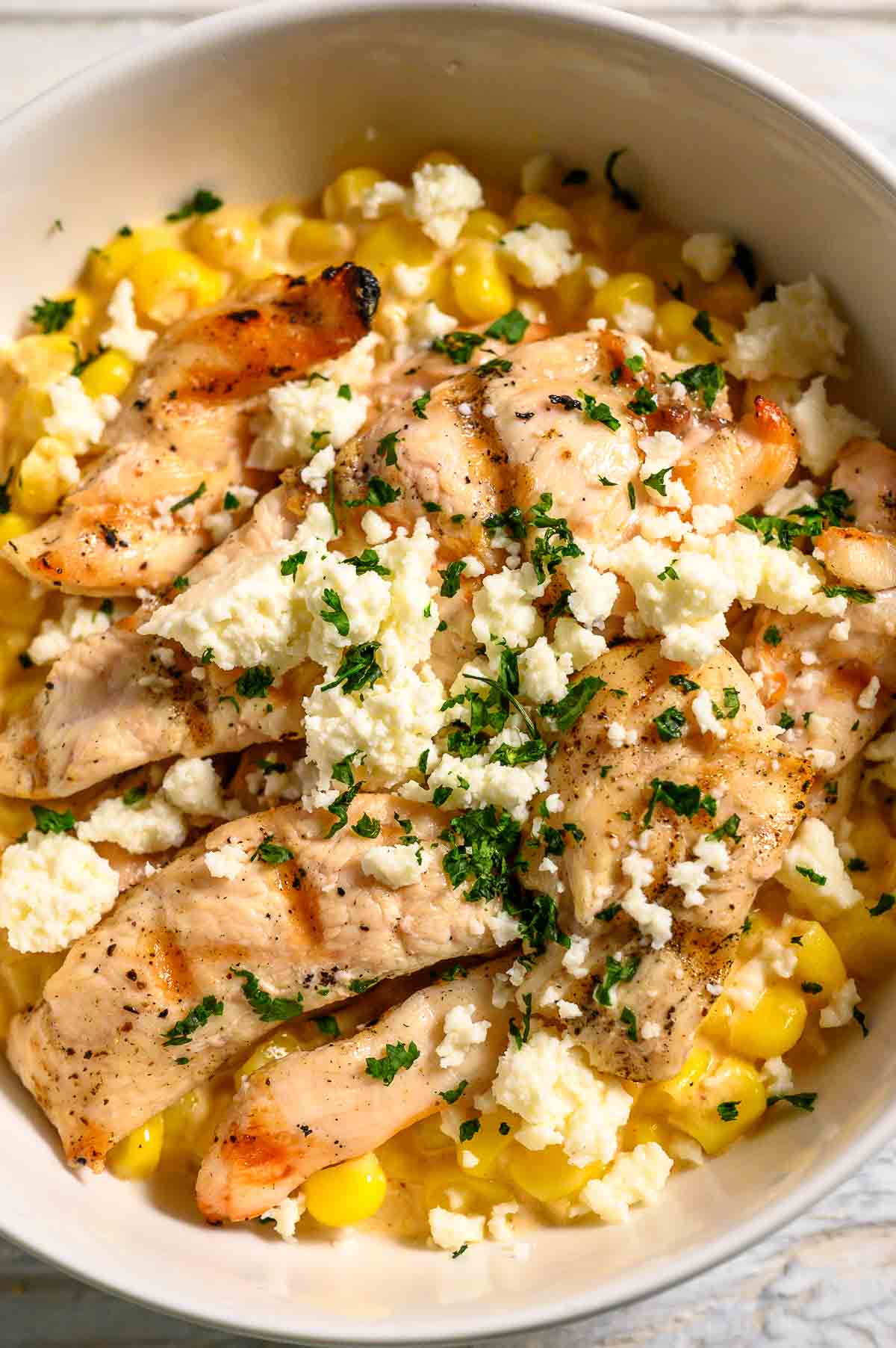 a bowl filled with corn, chicken, cheese, mayo sauce, and seasonings.