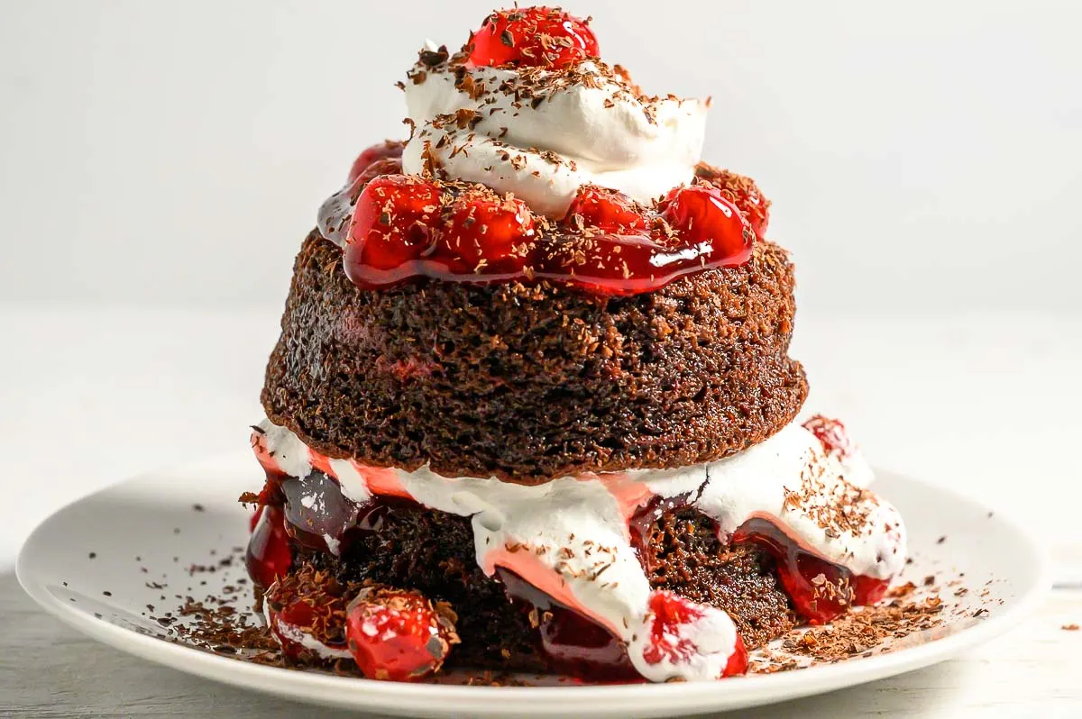 a small chocolate layer cake with cherries and whipped cream.