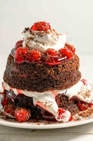 a small chocolate layer cake with cherries and whipped cream.