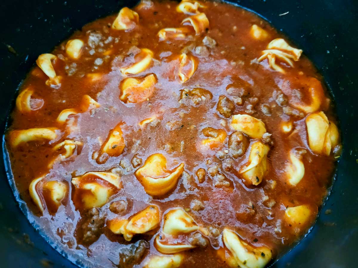 tortellini, marinara sauce, ground beef and seasonings cooking in a pan.