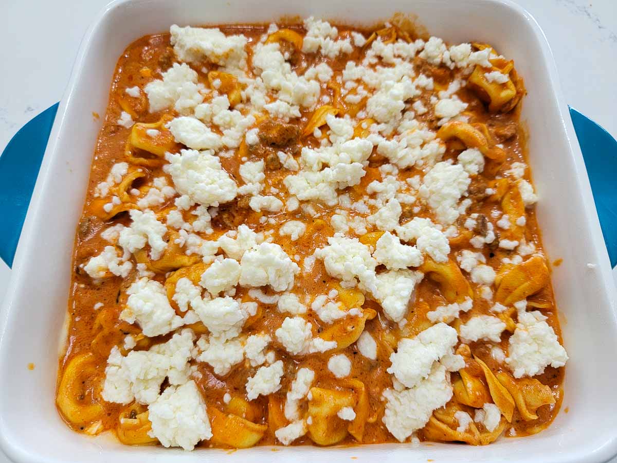 mozzarella cheese, cream cheese, tortellini, marinara sauce, ground beef and seasonings in a baking dish.