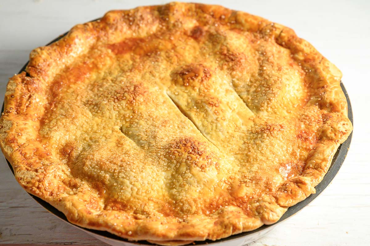 baked apple pie cooling in a pie pan.