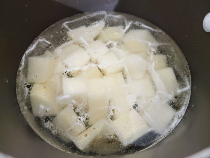 cubed potatoes cooking in a pan.