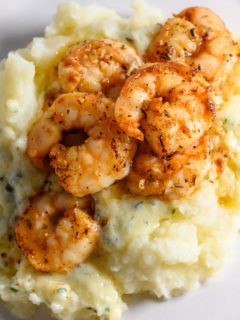 Shrimp and Mashed Potatoes with a thick, creamy basil and parmesan cheese sauce on a plate.