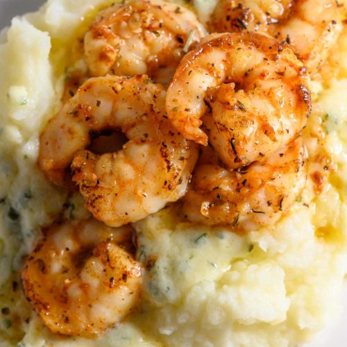 Shrimp and Mashed Potatoes with a thick, creamy basil and parmesan cheese sauce on a plate.