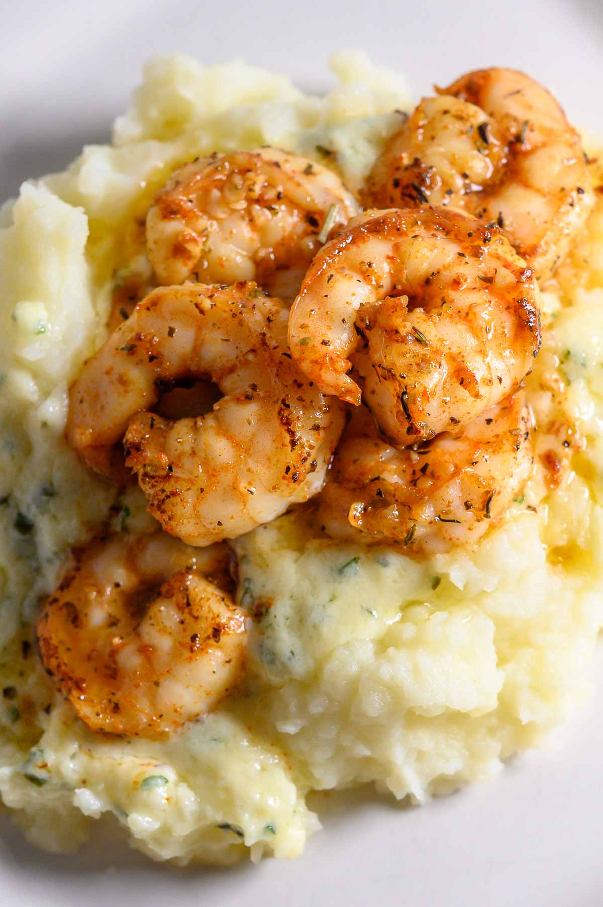 Shrimp and Mashed Potatoes with a thick, creamy basil and parmesan cheese sauce on a plate.
