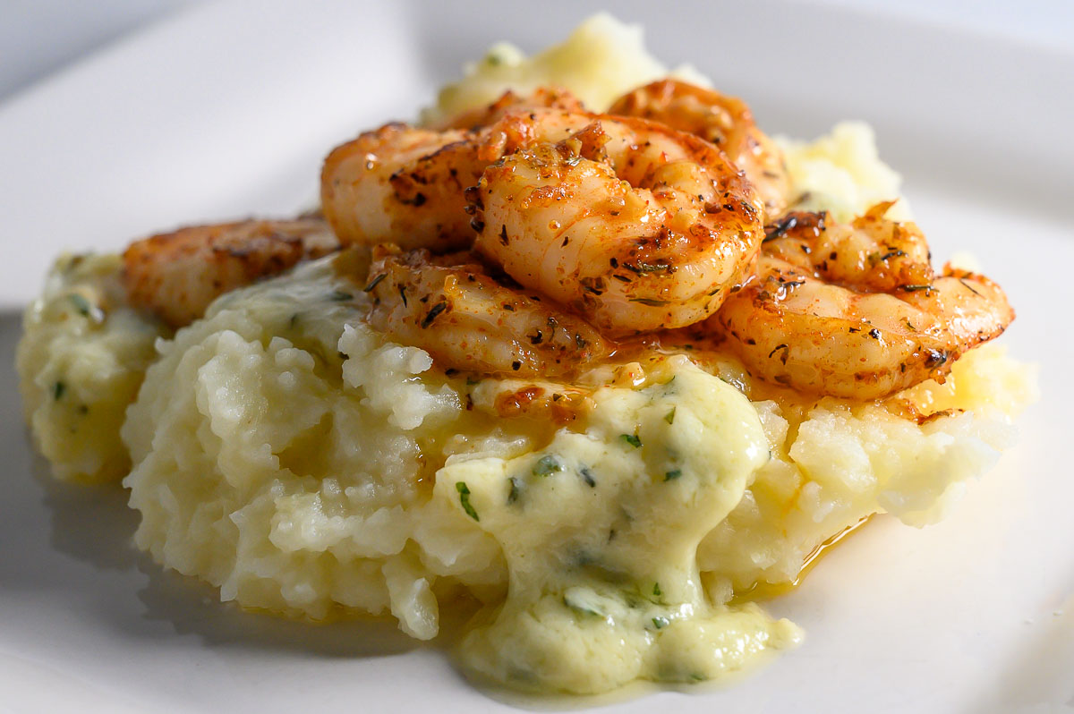 Shrimp and Mashed Potatoes with a thick, creamy basil and parmesan cheese sauce on a plate.