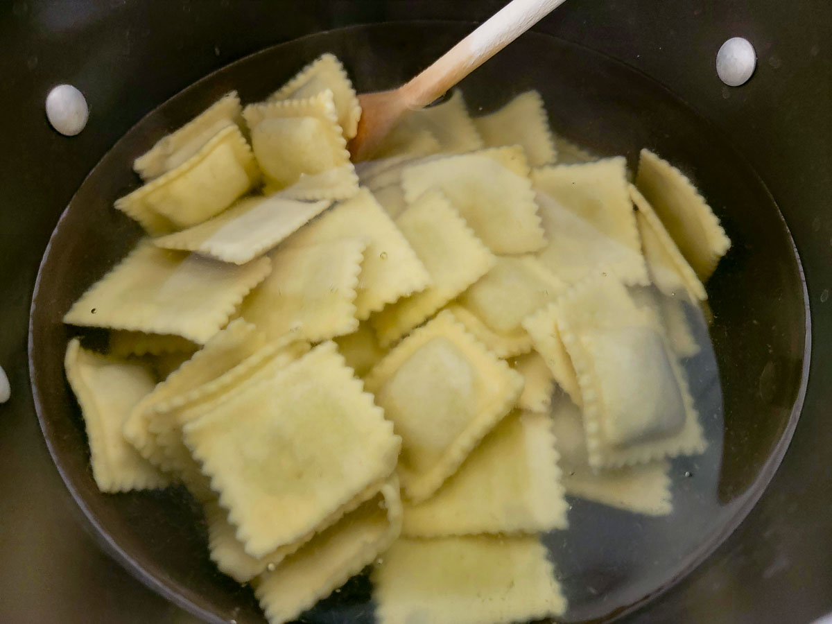 beef ravioli cooking in a saucepan of water.
