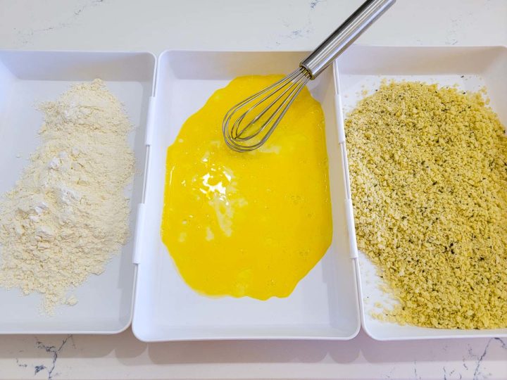 three dishes, first has flour, second has whisked egg, third has panko bread crumbs in it.