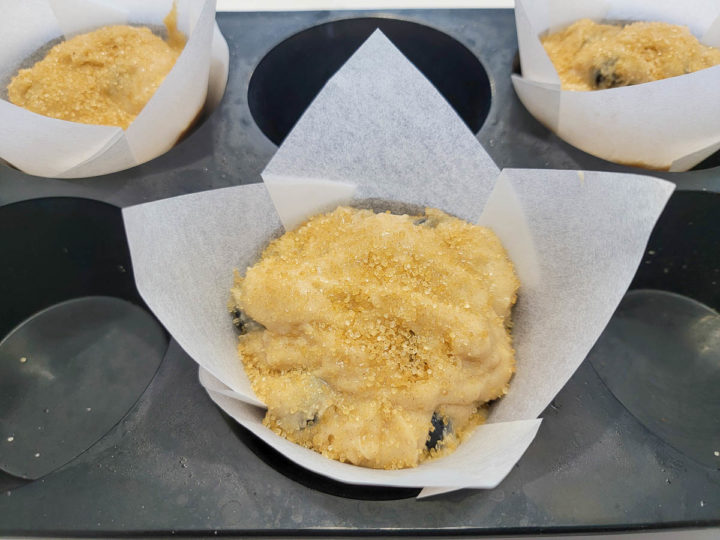 3 unbaked jumbo blueberry muffins in paper liners in a muffin pan.