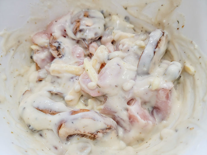 cheese, diced raw chicken, sliced mushrooms, chicken broth, cream of chicken soup, garlic powder, onion powder, Italian seasoning, and black pepper mixed in a bowl.