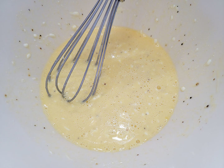 egg, milk, sour cream, and seasonings whisked in a bowl.