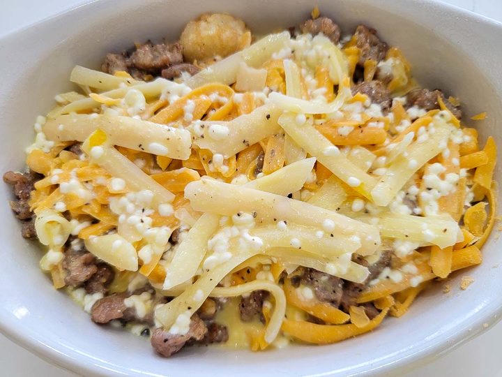 the tater tots, crumbled sausage, cheddar cheese, mozzarella cheese, egg, milk, sour cream, and seasonings in a baking dish..