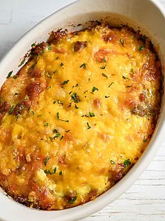 a baking dish with tater tot breakfast casserole filled with crispy tater tots, gooey cheese, savory sausage, and fluffy eggs.