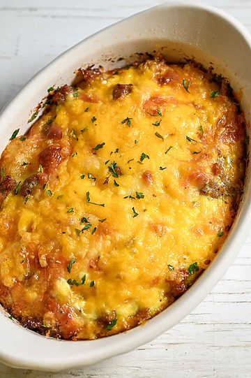 a baking dish with tater tot breakfast casserole filled with crispy tater tots, gooey cheese, savory sausage, and fluffy eggs.