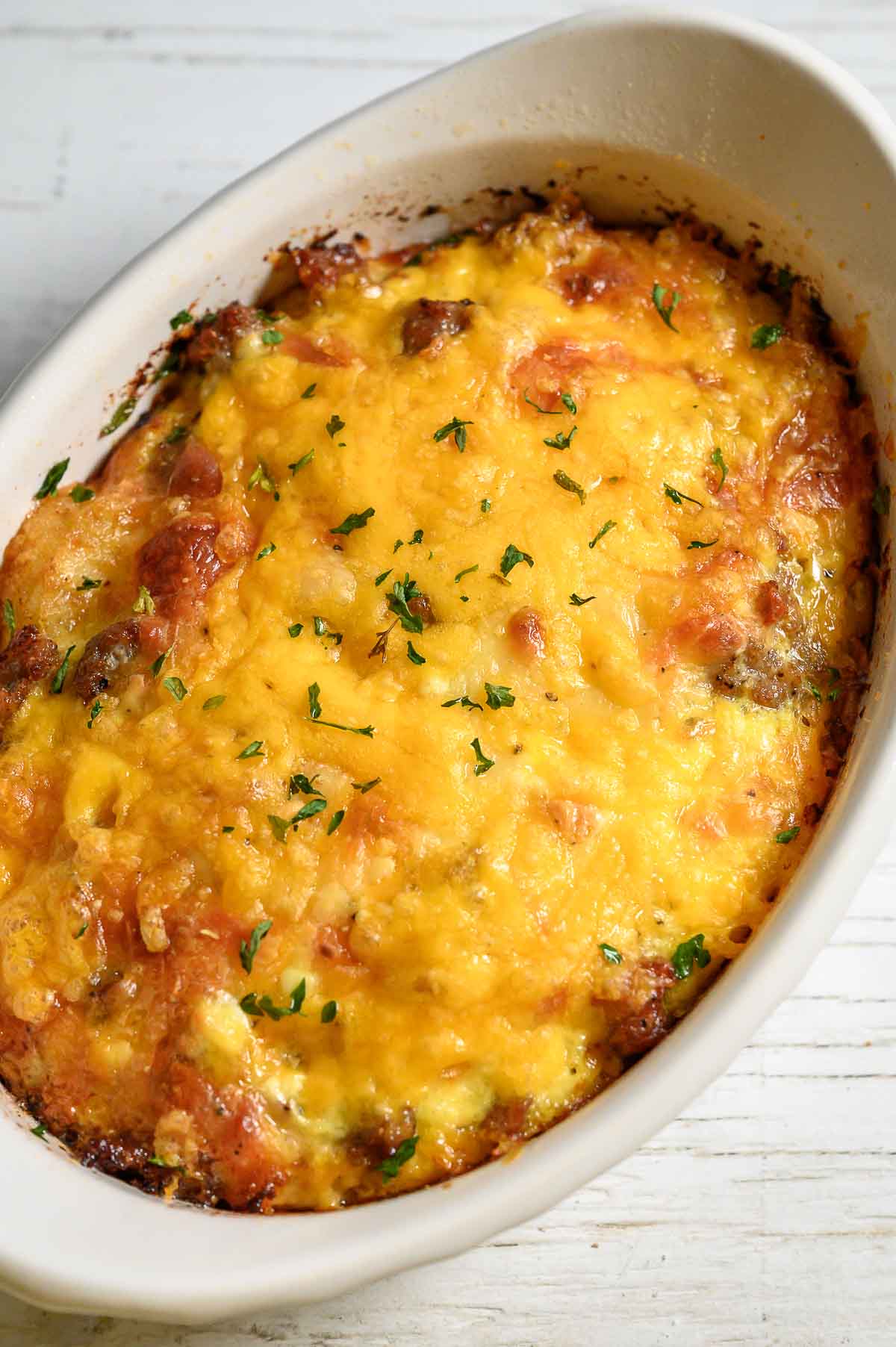 a baking dish with tater tot breakfast casserole filled with crispy tater tots, gooey cheese, savory sausage, and fluffy eggs.