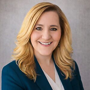 a professional portrait of zona house wearing a teal blazer.