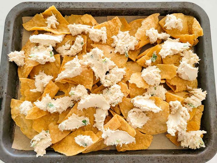 crab meat, cream cheese, green onion, Worcestershire sauce, soy sauce, and garlic powder over tortilla chips on a baking sheet.