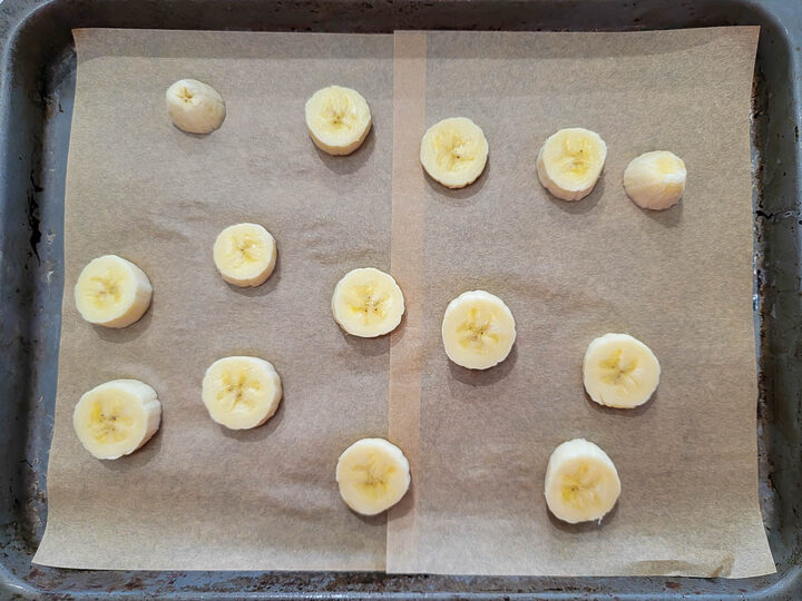 banana slices on a baking sheet lined with parchment paper.