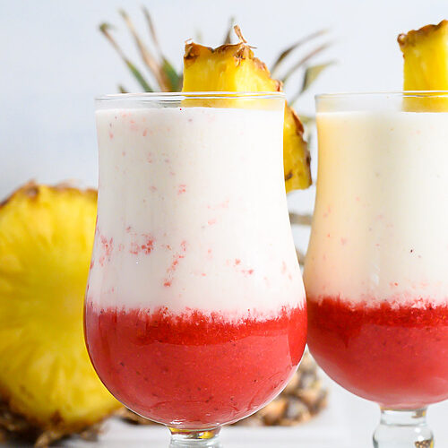 two Hawaiian Lava Flow Drinks garnished with pineapple wedges.