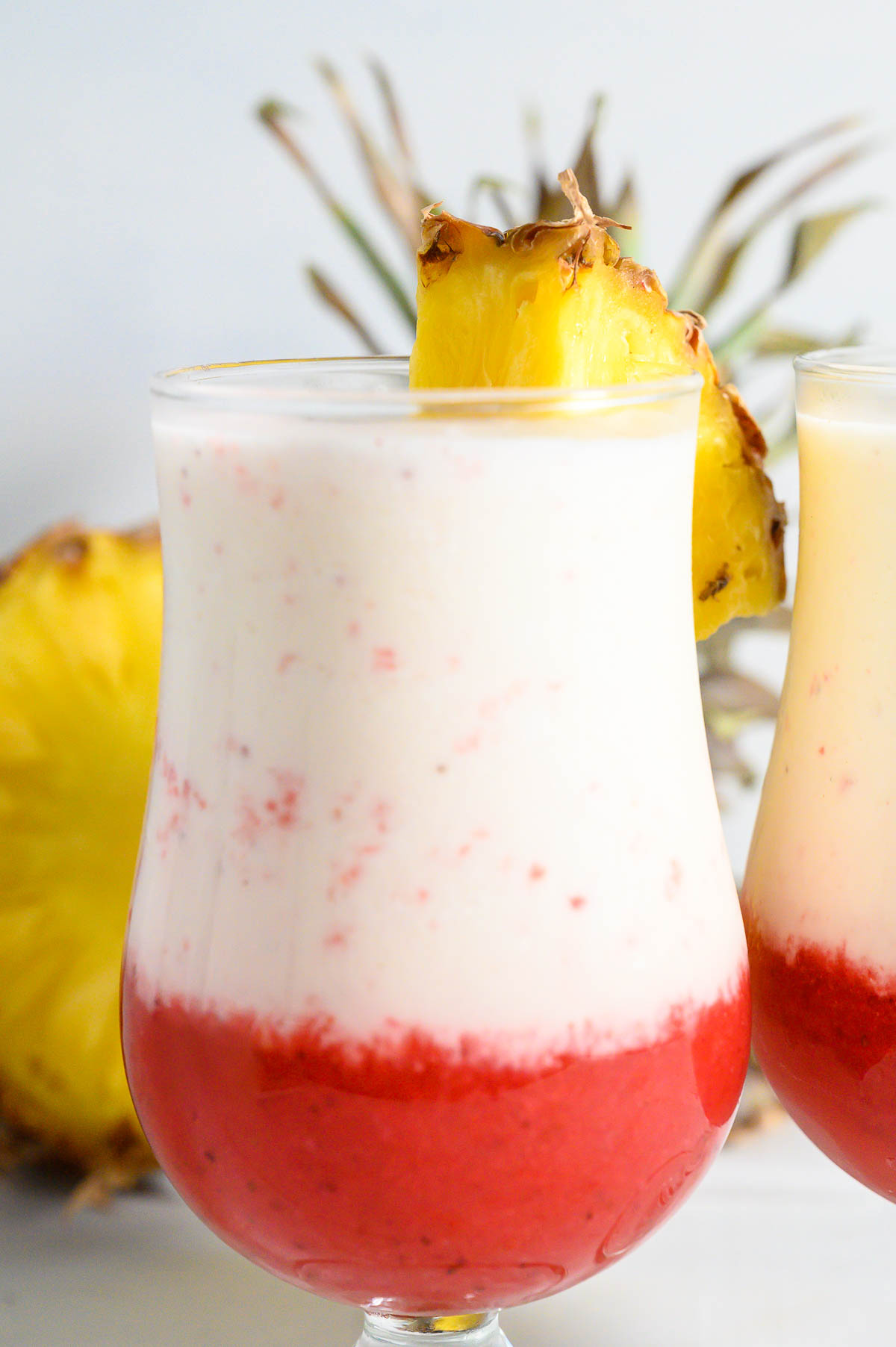 two Hawaiian Lava Flow Drinks garnished with pineapple wedges.