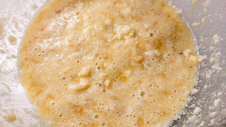 mashed banana, butter, sugar, eggs, and vanilla mixed in a bowl.