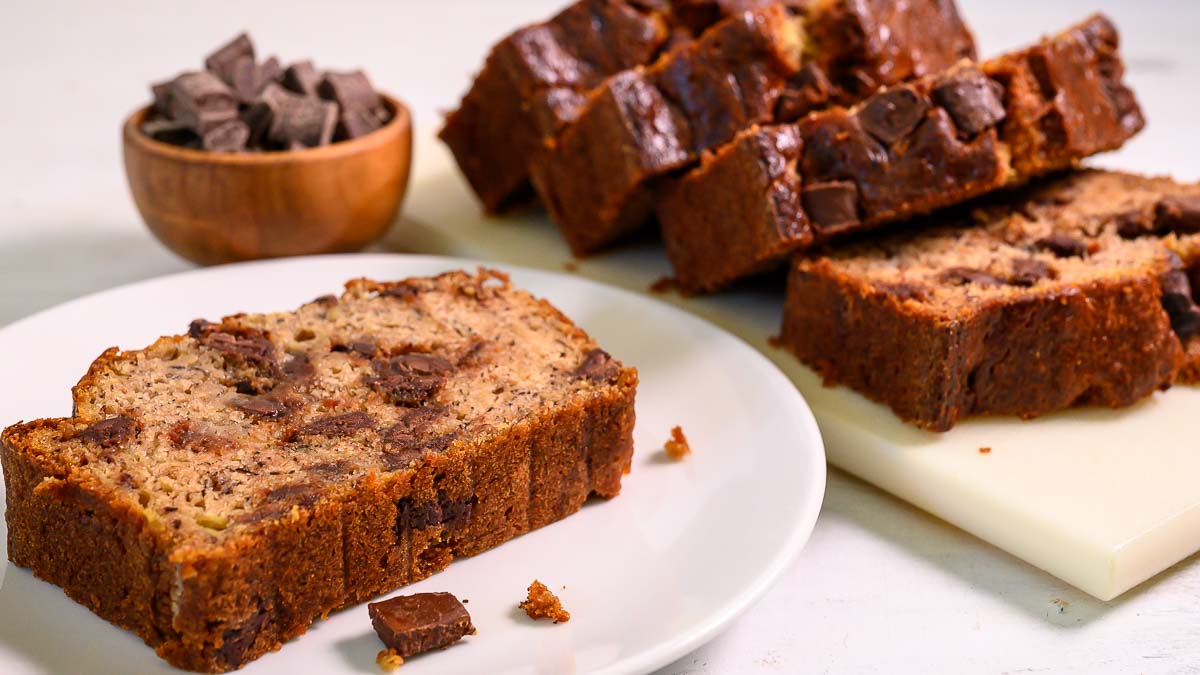 chocolate chunk banana bread slices on a plate and cutting board.