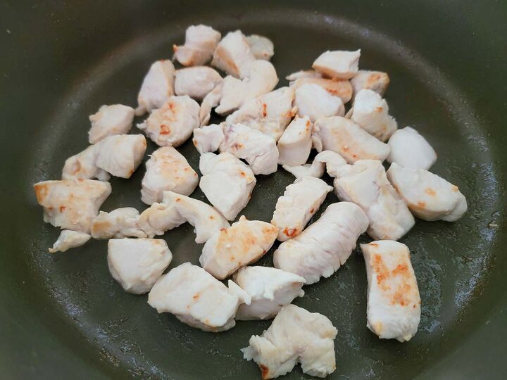 diced chicken cooking in a frying pan.